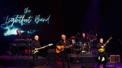 The Lightfoot Band on stage with a neon sign with the same text behind them.