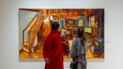Two women face away from the camera looking at an artwork in the galleries.
